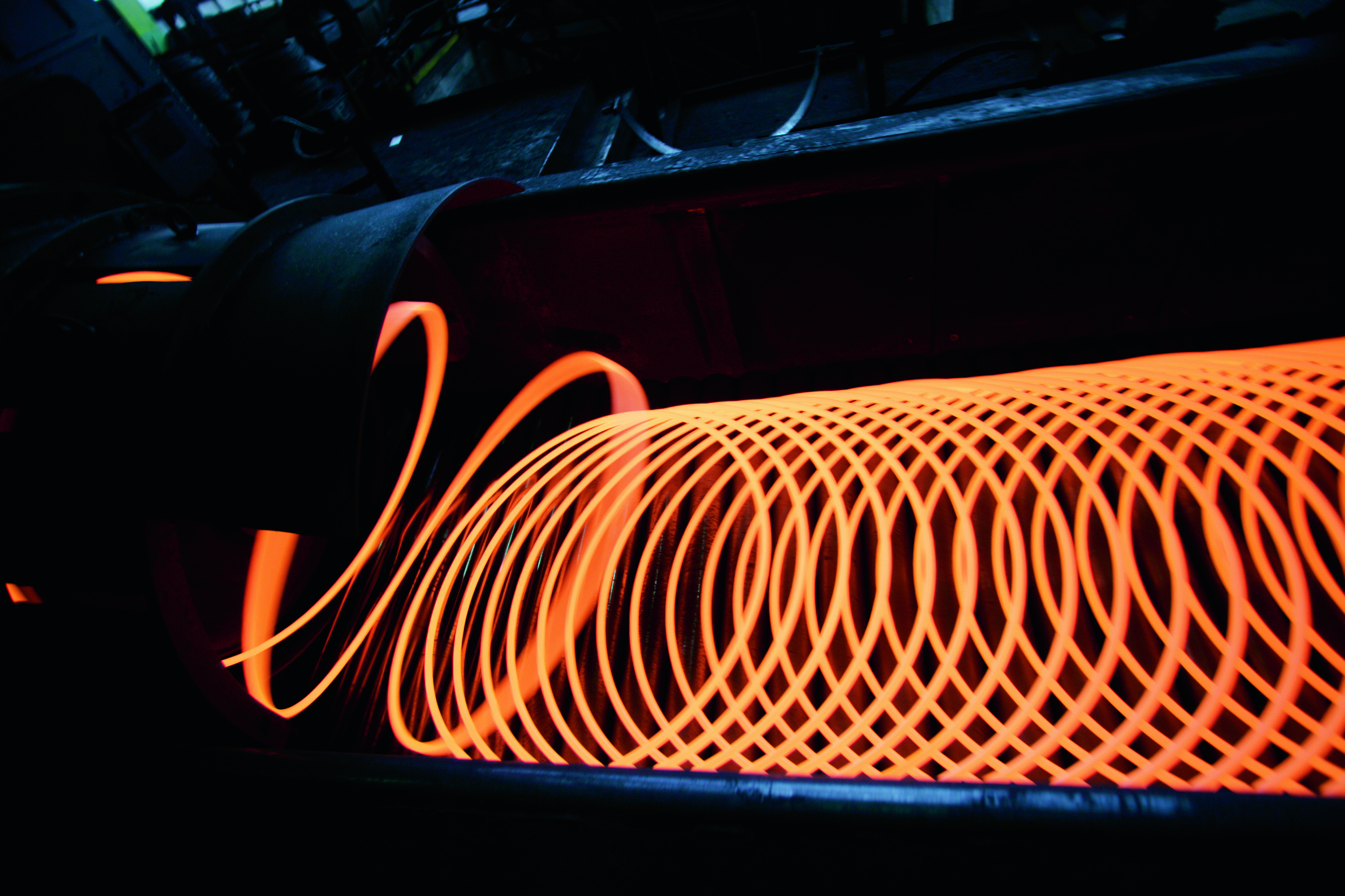 Glowing hot wire rod coil on dark background