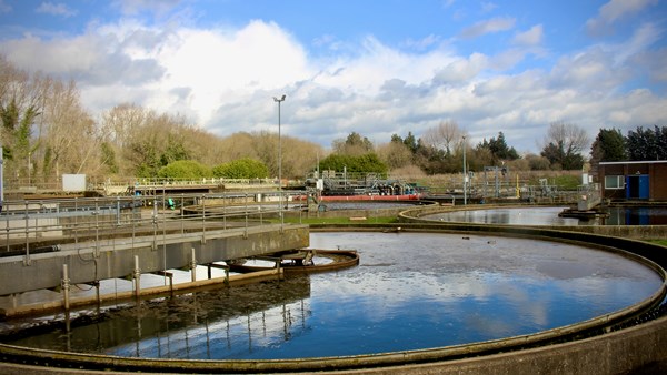 Blue sky and clouds mirrored in a circular aeration tank in a sewage treatment plant.